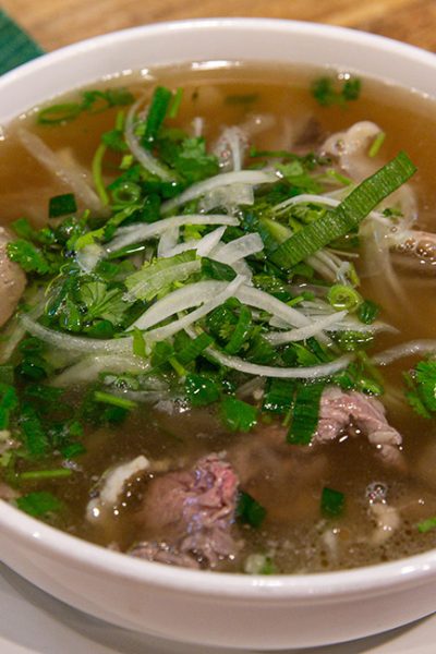 Classic Pho Bo with Beef Slices, Garnished with Basil and Lime in a Flavorful Vietnamese Broth